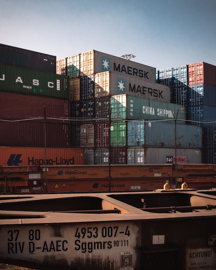 cta-02 A view of colorful cargo containers stacked at a bustling industrial harbor.