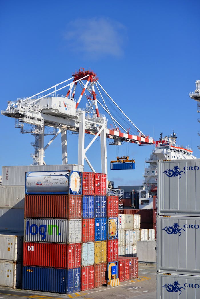 portfolio-02 Colorful shipping containers stacked in a busy port with cranes overhead.