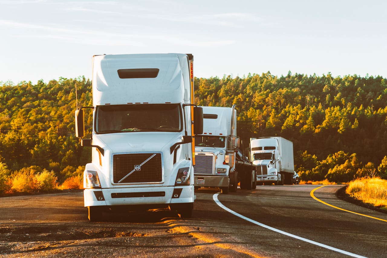 gallery-03 Three semi trucks driving on a highway through a forested landscape in Arizona.