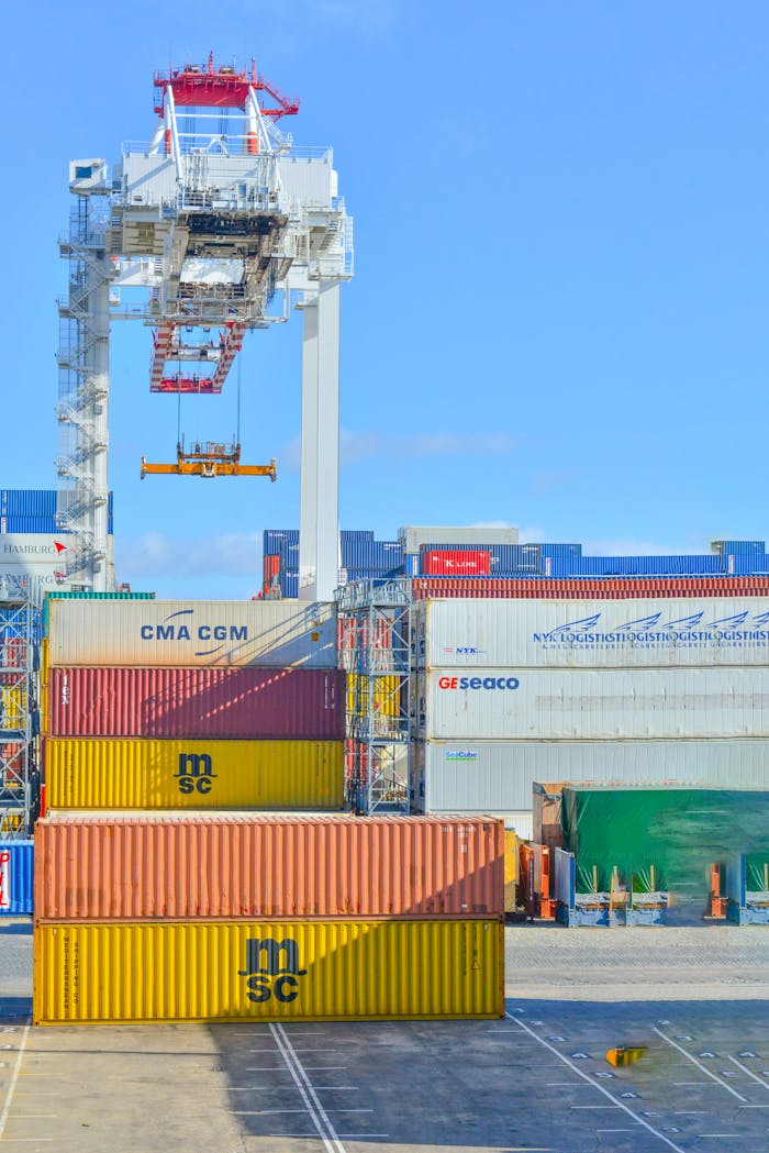 services-02 Stacked cargo containers in a sunny port industrial setting with crane.