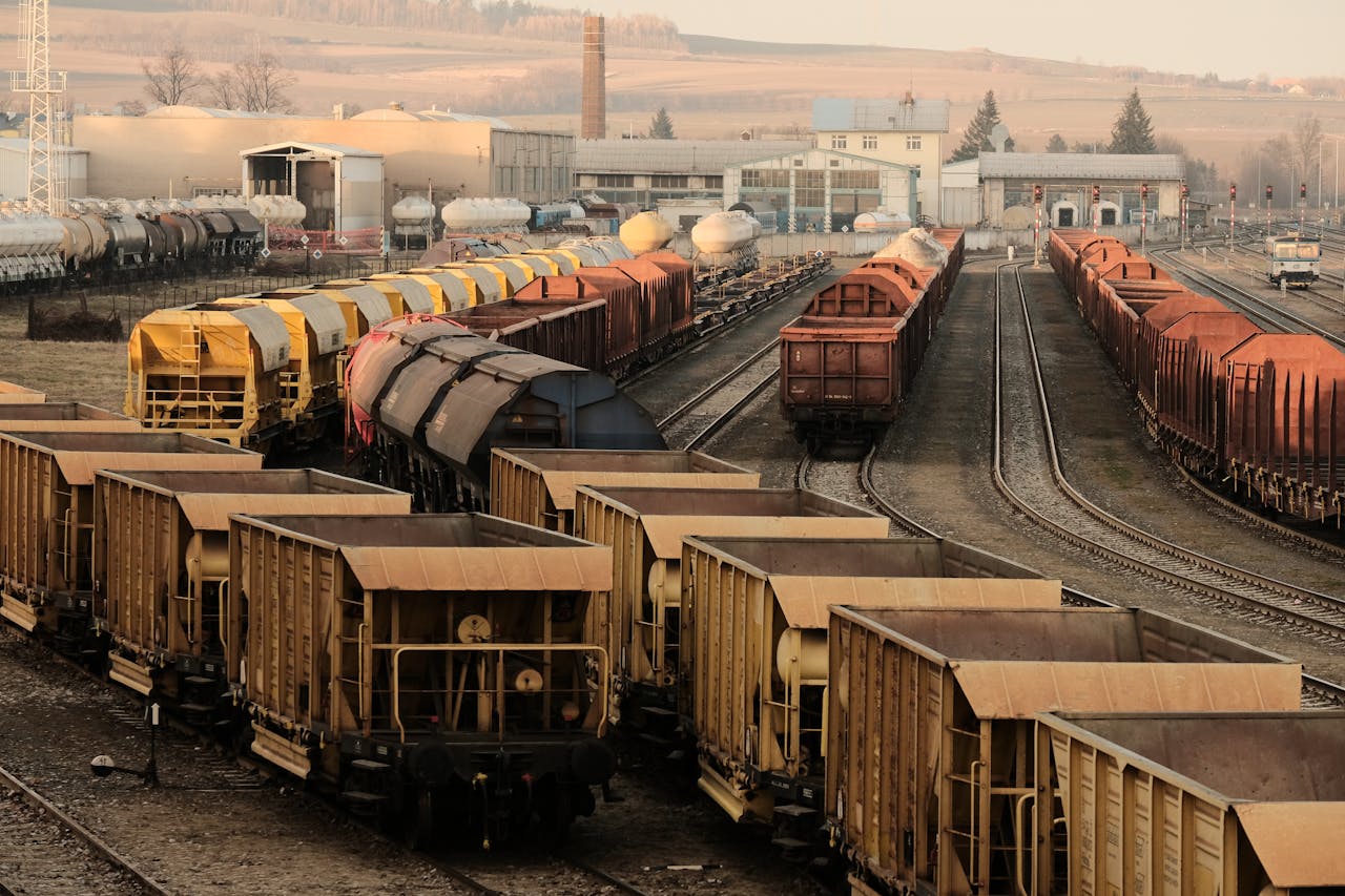 portfolio-04 A busy freight train yard with multiple tracks and a variety of train cars in a rural setting.
